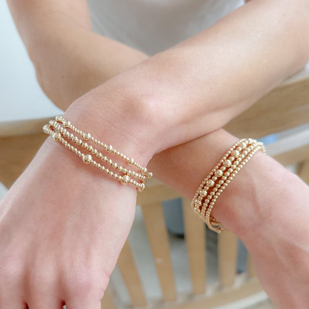 Two different and gorgeous gold beaded bracelets on corssing wrists, chic, stylish and timeless