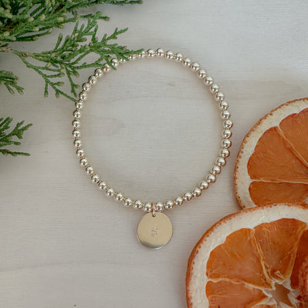 Timeless. Thoughtful. Giftable; A gold beaded bracelet with a hand-stamped letter disc—made just for them.