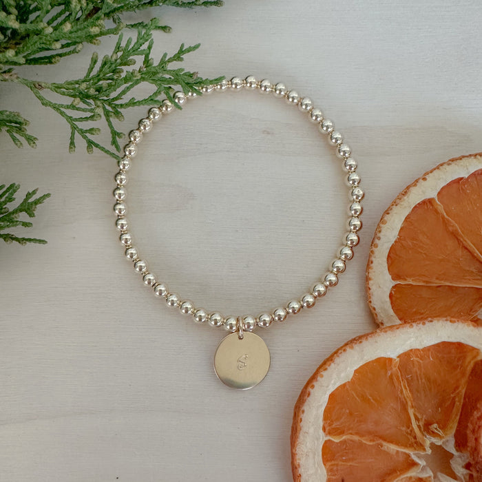 Timeless. Thoughtful. Giftable; A gold beaded bracelet with a hand-stamped letter disc—made just for them.
