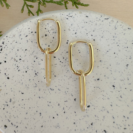 A pair of 14k gold filled double oval link hoop earrings on a marble surface.