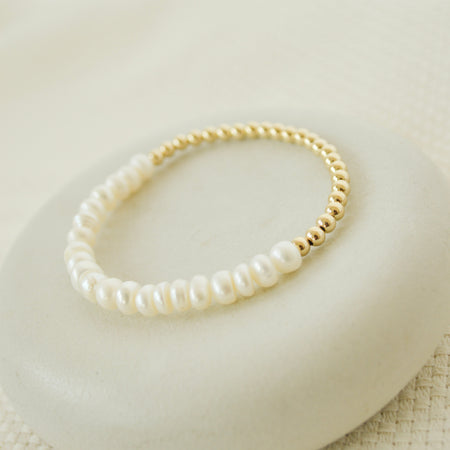 Pearl bracelet with gold clasp on a white surface