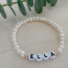A bracelet with gold filled beads and white acrylic beads with gold letters, featuring the name 'Ella'.