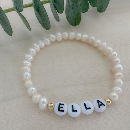 A bracelet with gold filled beads and white acrylic beads with gold letters, featuring the name 'Ella'.