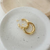 A pair of gold-filled hoop earrings placed on a white ceramic dish.