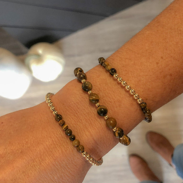 Close-up of a wrist wearing two beaded bracelets with a neutral background.