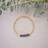 Gold bracelet with engraved name on a light background with green leaves