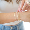 Person wearing gold bracelets on a blurred background