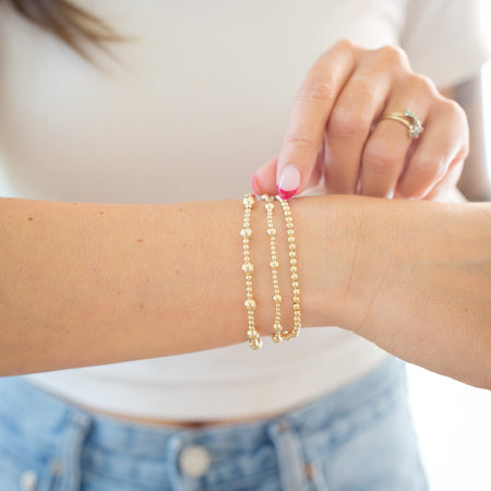 Close-up of a person wearing gold bracelets on a blurred background
