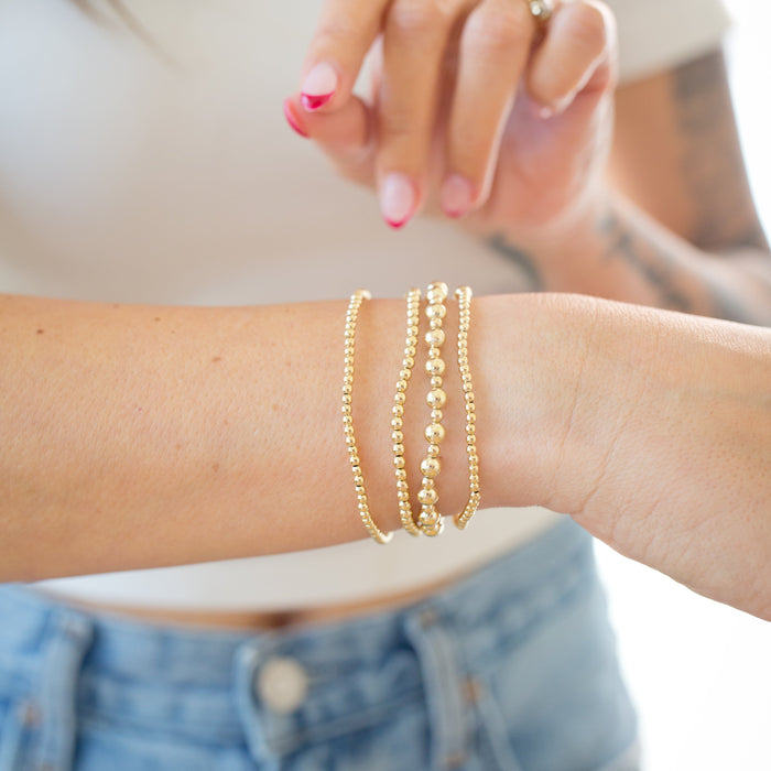 Gold bracelets on a wrist with a blurred background