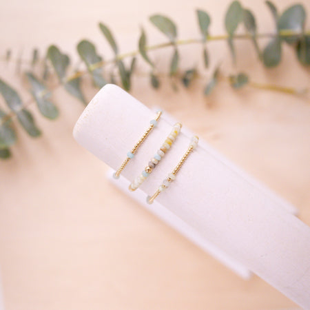 gold and amazonite beaded bracelets on jewelry arm with wood light backgrop