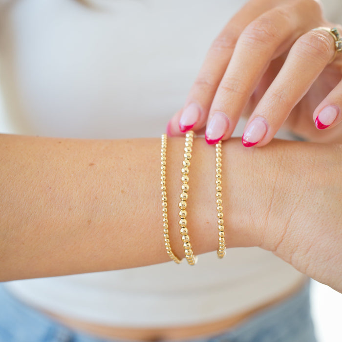 Gold bracelets on a wrist with a blurred background
