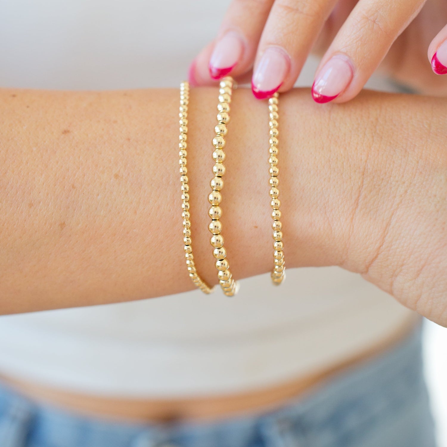 Gold bracelets on a wrist with a blurred background