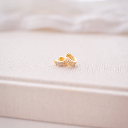 Gold earrings on a soft white fabric background