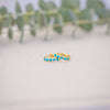 Gold ring with turquoise stones on a textured surface with blurred greenery in the background