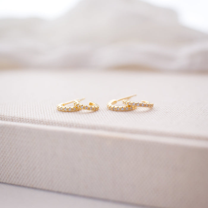 Gold earrings on a white satin surface