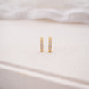 Gold hoop earrings on a soft white fabric background