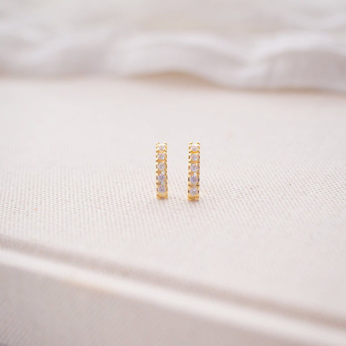 Gold hoop earrings on a soft white fabric background