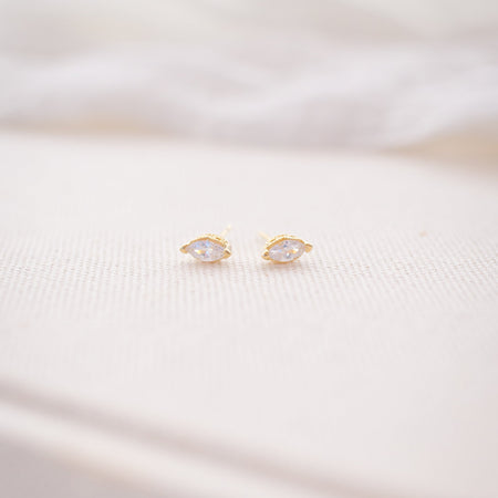 Gold earrings on a soft white fabric background