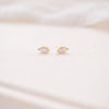 Pair of gold earrings on a soft white fabric background
