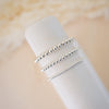 Three silver beaded rings on a white cylindrical stand against a beige background