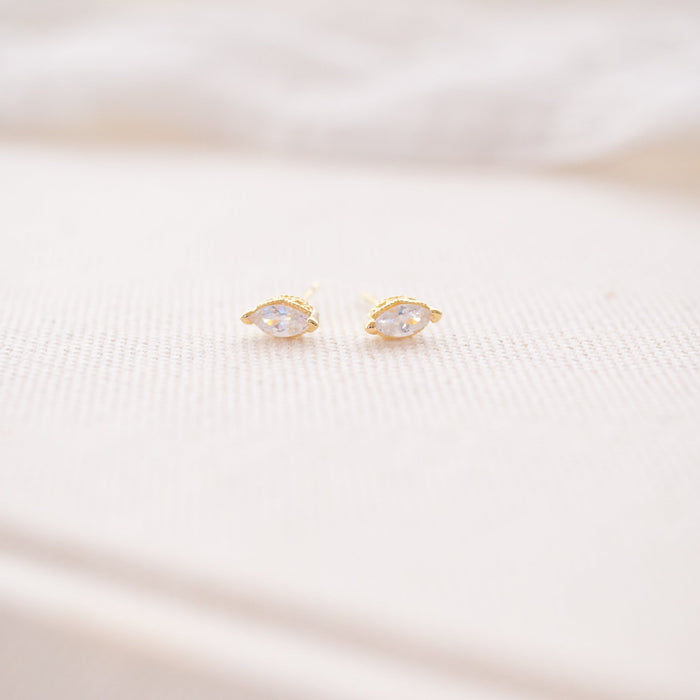 Pair of gold earrings on a soft white fabric background