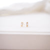 Gold earrings on a white surface with a blurred background