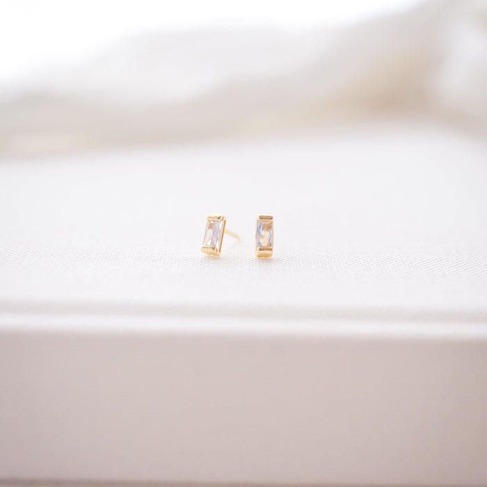Gold earrings on a white surface with a blurred background