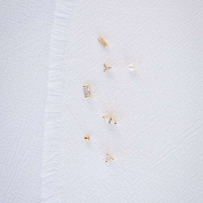 Close-up of a white textured fabric with small gold embellishments on a light gray background