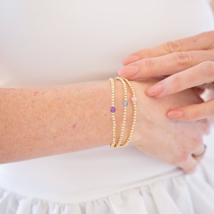 Gold bracelets on a wrist with a white background