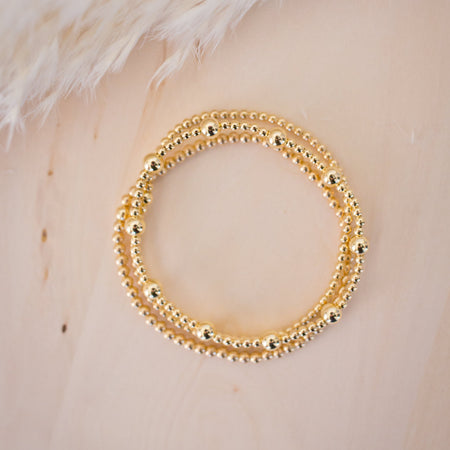 Gold beaded bracelet on a light background