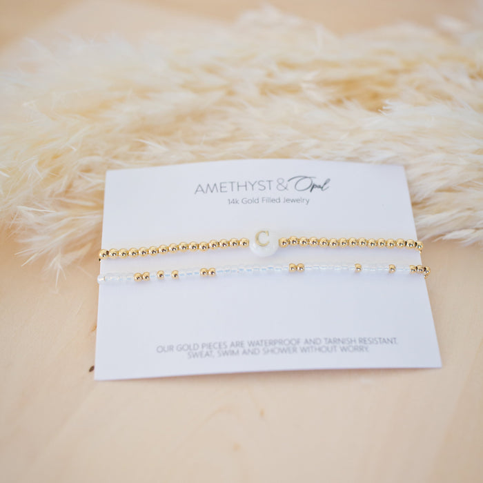 Gold bracelet on a card with 'Aimee Rose & Co.' branding against a textured beige background