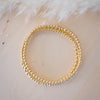 Gold beaded bracelet on a textured white surface
