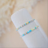 Two beaded bracelets on a white cylindrical object with a soft beige background