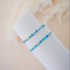 Two turquoise beaded bracelets on a white cylindrical object with a blurred background