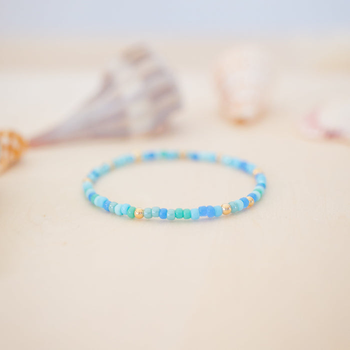 Blue beaded bracelet on a person's wrist with a blurred background