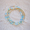 Stack of blue and gold beaded bracelets on a beige surface