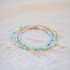 Two beaded bracelets with blue and gold accents on a light background