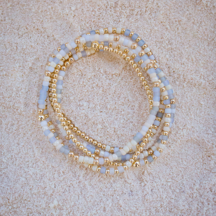 Set of beaded bracelets with gold accents on a beige surface