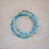 Set of blue and gold beaded bracelets on a beige surface