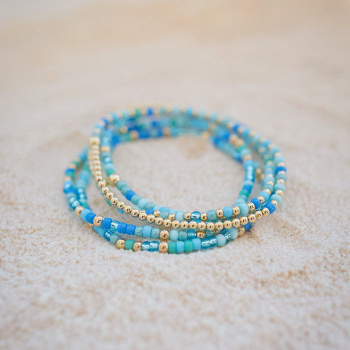 Stack of blue beaded bracelets on a light surface