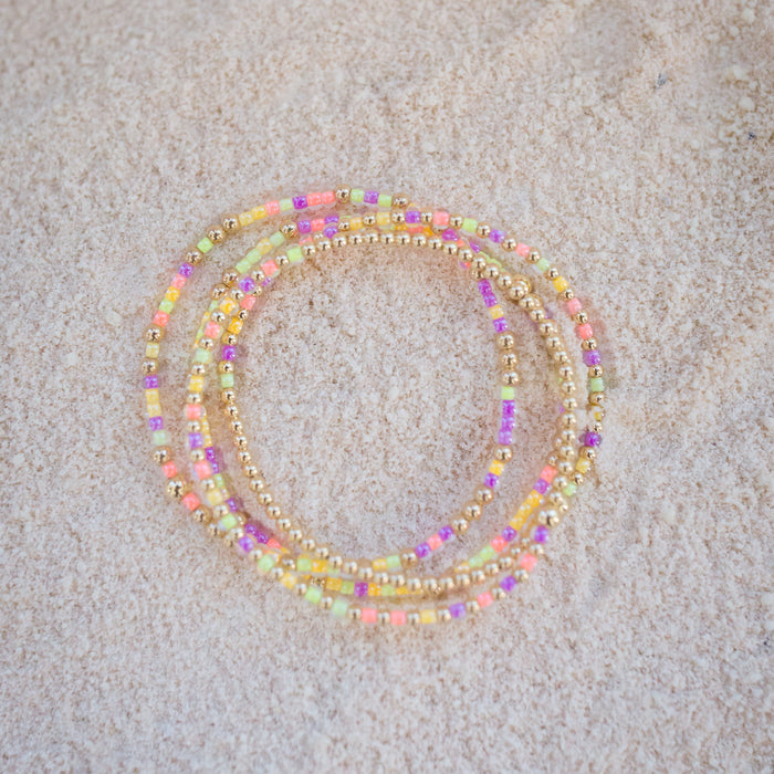 Set of colorful beaded bracelets on a beige sand