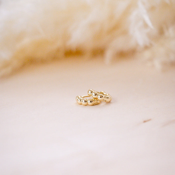 tiny huggies with gold ball texture on wood background