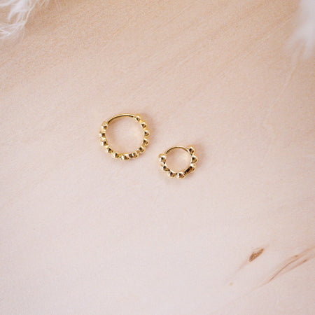 tiny huggies with gold ball texture on wood background shown in two size options