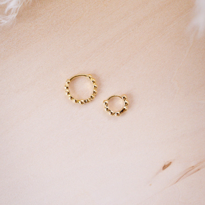 tiny huggies with gold ball texture on wood background shown in two size options
