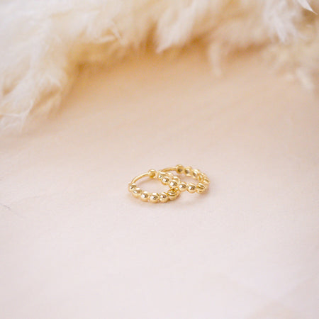 tiny huggies with gold ball texture on wood background