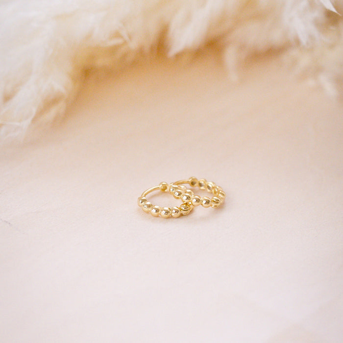 tiny huggies with gold ball texture on wood background
