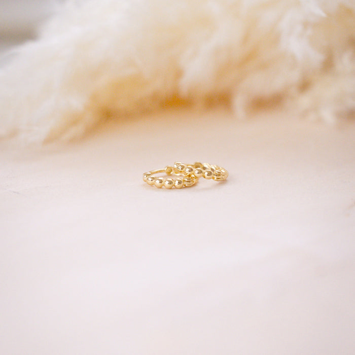 tiny huggies with gold ball texture on wood background