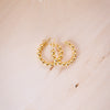 A close-up image of a person's ear wearing a gold filled beaded hoop earring.