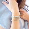 Close-up of a person wearing multiple beaded bracelets on a blurred background