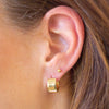 Close-up of a person wearing a gold hoop earring.